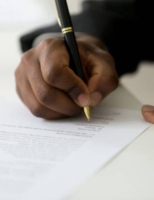 Close up of African American worker signing job contract, person being employed at new position, male client putting signature at document in office. Recruiting, promotion, legal documentation concept